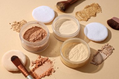 Yüz pudrası şişeleri, farklı gölgeler, pastel arka planda..