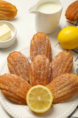 Madeleine kekleri, limonlar, tereyağı ve süt sürahisi arka planda, kapatın.