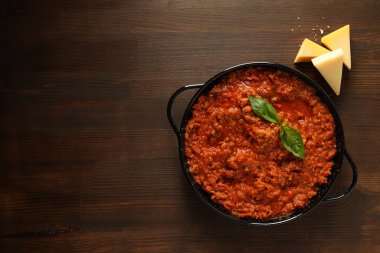 Kızartma tavasında bolonez sosu ve ahşap arka planda peynir parçaları, metin için yer