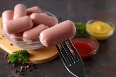 Siyah arka planda şeffaf bir kasede küçük sosisler.