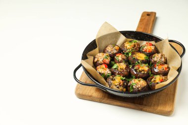 Kızartma tavasına ve mutfak tahtasına doldurulmuş mantarlar beyaz arka planda, mesaj için boşluk