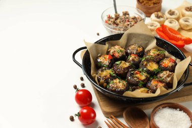 Kızartma tavasına doldurulmuş mantar, mutfak tahtası ve malzemeler beyaz arka planda, metin için yer