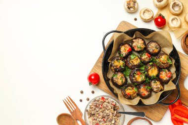 Kızartma tavasına doldurulmuş mantar, mutfak tahtası ve malzemeler beyaz arka planda, metin için yer