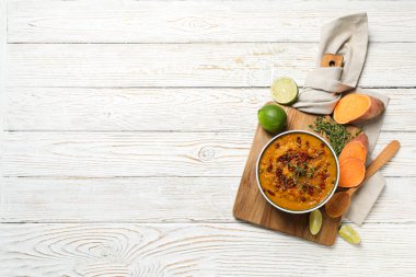 Tatlı patates püresi kasede ve mutfak tahtasındaki malzemeler ahşap arka planda, mesaj için yer var.