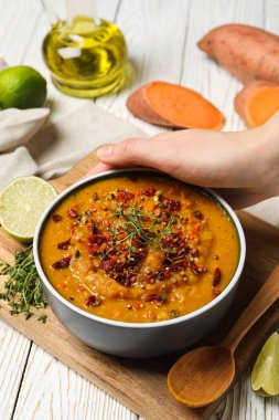 Tatlı patates püresi kasede, elde, mutfak tahtasındaki malzemeler ahşap arka planda, kapat.