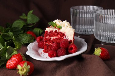 Tabakta kırmızı kadife kek, cam, böğürtlen ve kahverengi arka planda nane