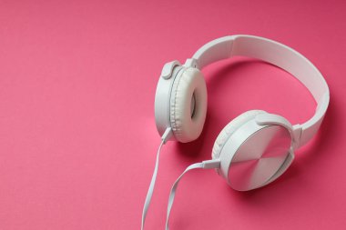 Beyaz, kulaklıklı, pembe arka planda dinleme cihazı olan..
