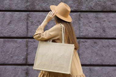 Şapkalı bir kadın ve omzunda bir çanta.