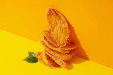 Sarı arka planda kurutulmuş mango cipsi.
