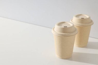 Paper cups with lids on a light background clipart