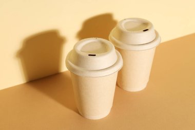 Paper cups with lids on a light background clipart