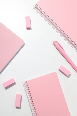 Beyaz zemin üzerinde kırtasiye malzemesi olan pembe defter