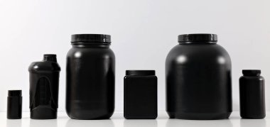 Beyaz arkaplanda siyah plastik kavanozlar ve şişe, metin için boşluk