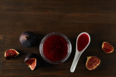 İncir, reçel kavanozu ve tahta arka planda kaşık, metin için boşluk