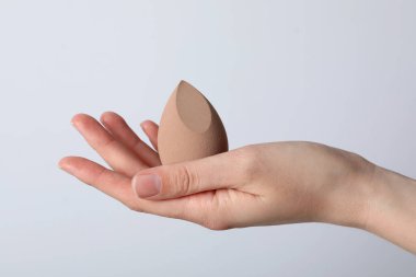 Beyaz arkaplanda elinde makyaj süngeri