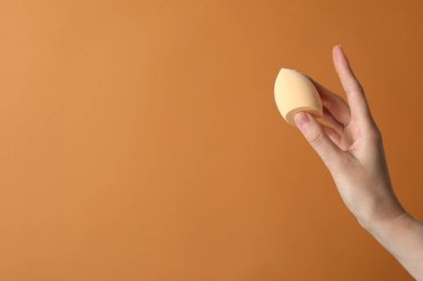 Bej arka planda elinde makyaj süngeri