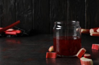 Kavanozda raventli jöle ve taze ravent kökü koyu arkaplanda.