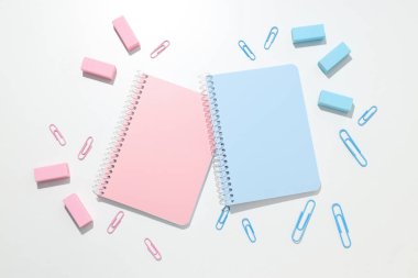 Beyaz zemin üzerinde kırtasiye malzemesi olan mavi ve pembe defterler