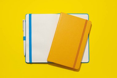 Sarı arka planda iki defter var.