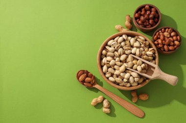 Yeşil arka plandaki ahşap kaselerde farklı türde fındıklar.