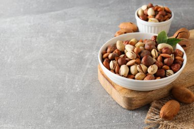 Gri arka planda beyaz kaselerde çeşitli fındıklar.