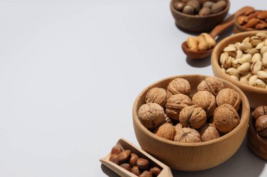 Gri arka planda ahşap kaselerde çeşitli fındıklar