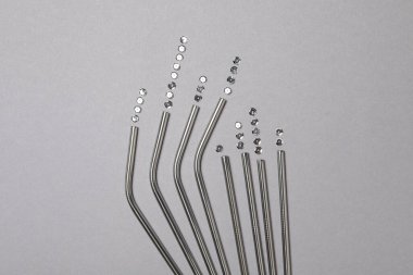 Gri arka planda metal yeniden kullanılabilir kokteyl pipetleri ve pulları, üst görünüm