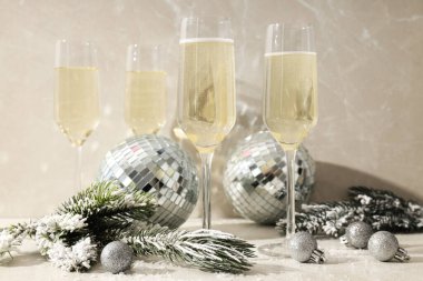 Hafif arka planda Noel topları olan şampanya kadehleri.