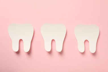 Bakım için diş aletleri olan dişler, pembe arka planda.