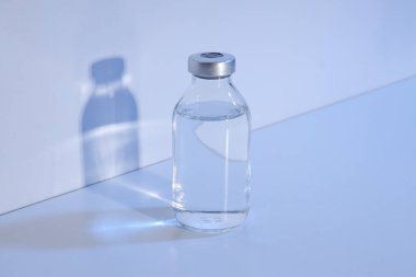 Işık arka planında sıvı bulunan cam tıbbi şişe.