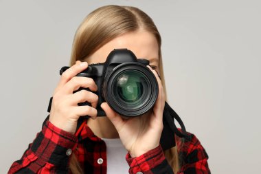 Neşeli fotoğrafçı kız, gri arka planda..