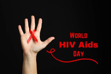AIDS günü, kırmızı kurdele elinde siyah arkaplanda metin ile