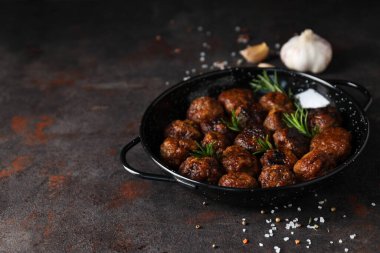 Siyah bir kasede siyah bir arka planda köfteler.