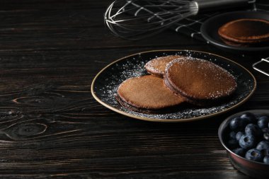 Tabaklarda çikolatalı gözleme ve tahta arka planda böğürtlenli kase, metin için yer var.