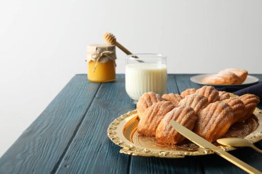 Madeleine kekleri, bir bardak süt ve arka planda bir kavanoz bal, metin için yer