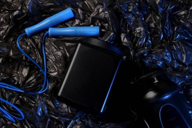 Zıplama ipi, siyah plastik kavanoz ve siyah arka planda şişe, üst manzara.