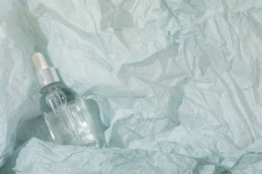 Hafif arka planda şeffaf bir şişede kozmetik yağ