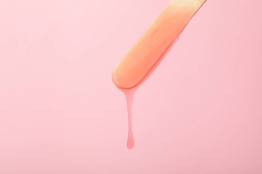 Pembe arka planda tüy dökmek için tahta bir çubuk.