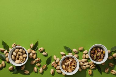 Yeşil arka planda, bir tabakta fıstıklar..