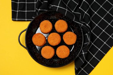 Sarı arka planda siyah kaselerde kızarmış mozzarella.