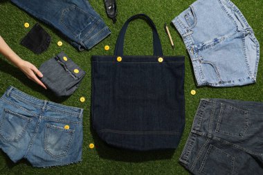 Kot pantolon ve çantalar, yeşil arka plan, üst manzara.