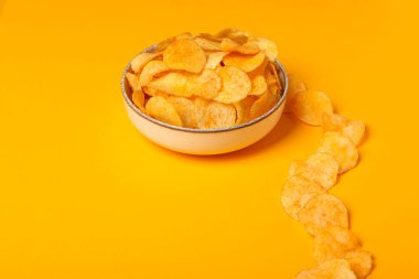 Sarı arka planda bir kasede patates cipsi