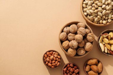 Bej arka planda ahşap kaselerde çeşitli fındıklar