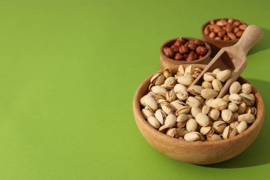 Yeşil arka plandaki ahşap kaselerde farklı türde fındıklar.