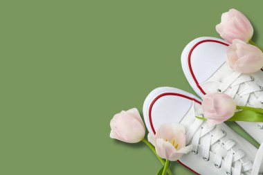 Merhaba ilkbahar, yeşil arka planda beyaz spor ayakkabılar ve laleler, üst manzara, metin için yer