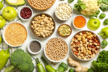 Kâselerde vejetaryen protein ürünleri ve beyaz arka planda havlu, üst görünüm.