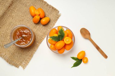 Kumkuat kasede, reçel kavanozu ve tahta kaşık beyaz arka planda, üst manzara