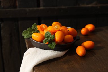 Kumkuat kasede ve beyaz havlu koyu ahşap arka planda.