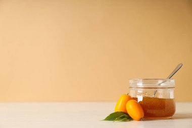 Bej arkaplanda Kumquat ve kavanoz reçel, metin için boşluk