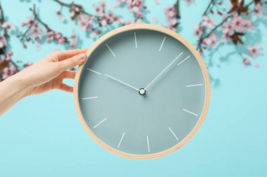 Bahar Perdesi. Mavi bir arka planda, bir saati tutan el..